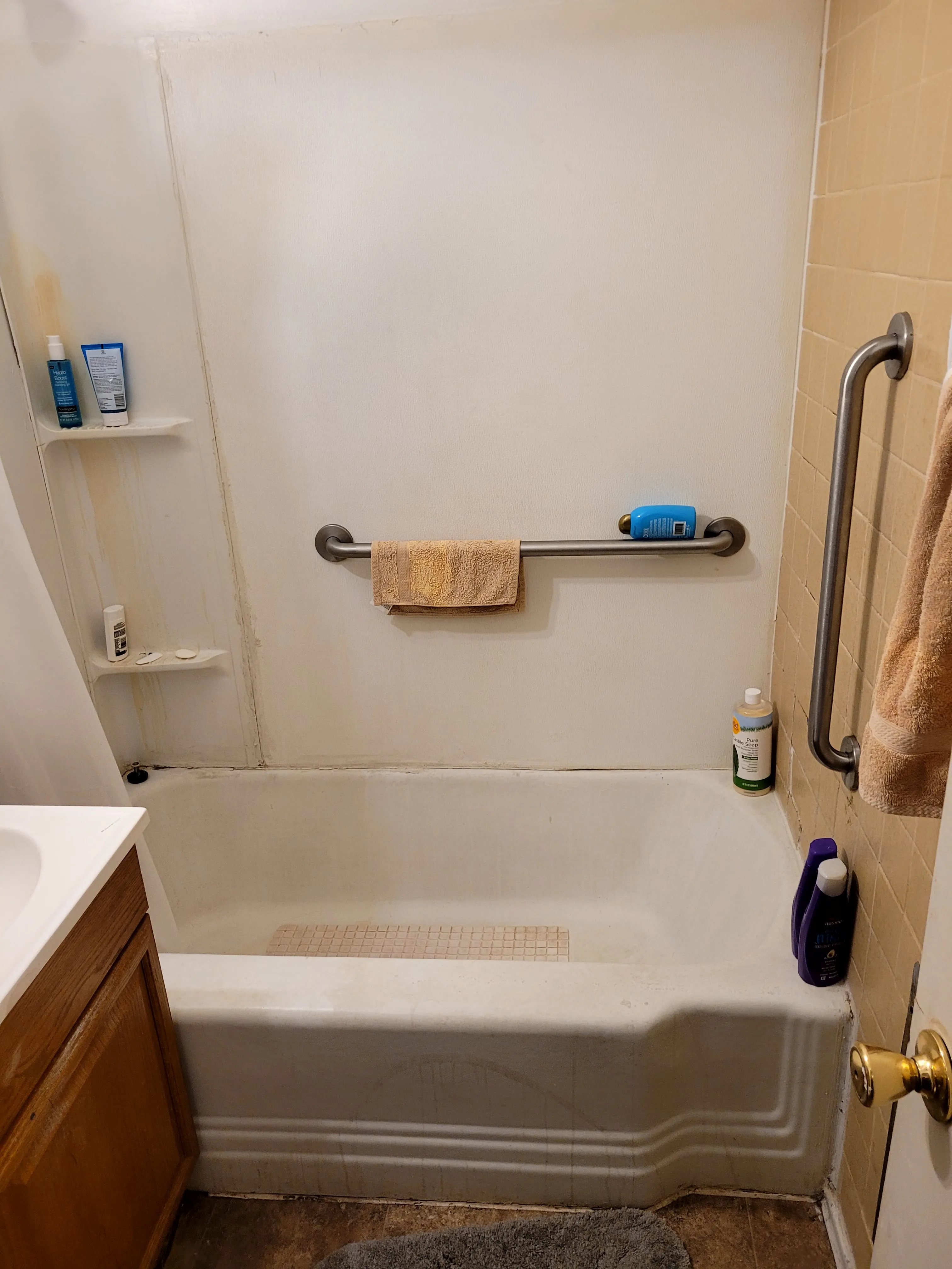 Before — Small bathroom remodel. Before: dingy old yellow 4x4 tile, dated wood vanity, scratched cast-iron tub. After: white subway tile with dark grout, hex floor tile, new sink and tub. Yellow tile remnants still visible behind new subway tile in after shot confirms same room.